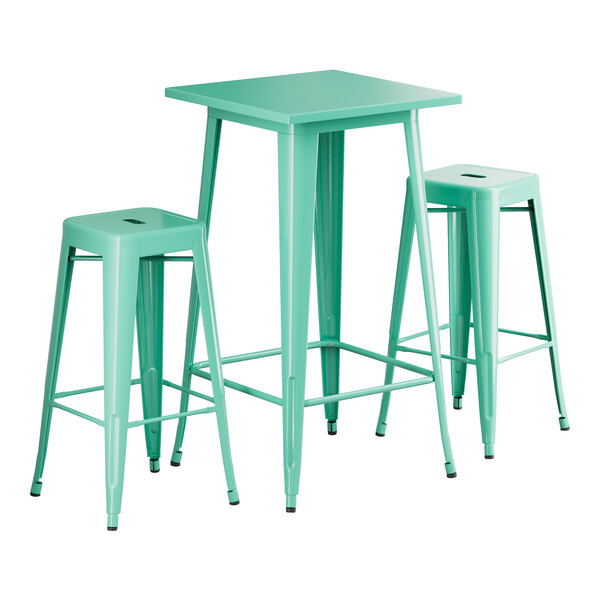 A Lancaster Table & Seating bar height outdoor table in aquamarine with two backless barstools with green seats.