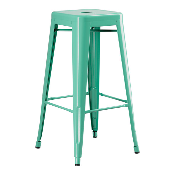 A Lancaster Table & Seating aquamarine metal bar height table with a green metal stool with legs.
