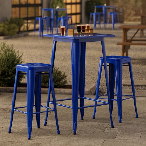 A Lancaster Table & Seating blue metal bar height table with blue quartz top and 2 blue barstools.