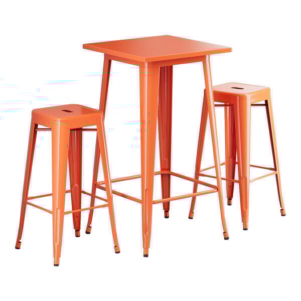 A Lancaster Table & Seating bar height outdoor table in amber orange metal with two backless barstools.