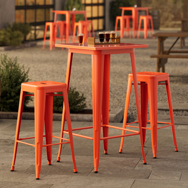 An outdoor table with barstools. The table and barstools are orange.
