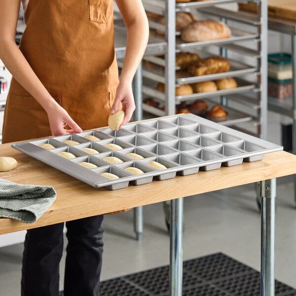 A 28-compartment glazed aluminized steel mini bread pan with rectangular cavities, used for baking small loaves of bread.