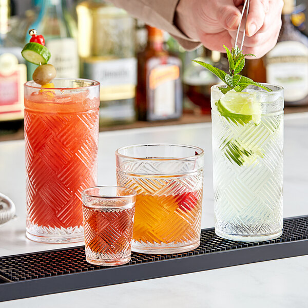 A bartender pours drinks into Acopa Zion highball glasses on a table in a cocktail bar.