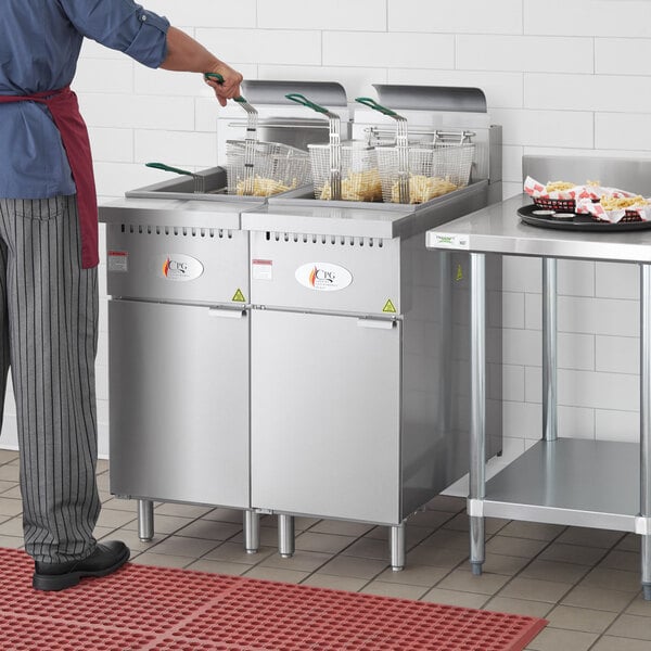 A man standing next to a Cooking Performance Group stainless steel connector strip for fryers in a large commercial kitchen.