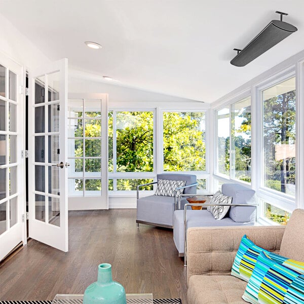 An Aura Shadow Black electric infrared patio heater above a couch with colorful pillows.