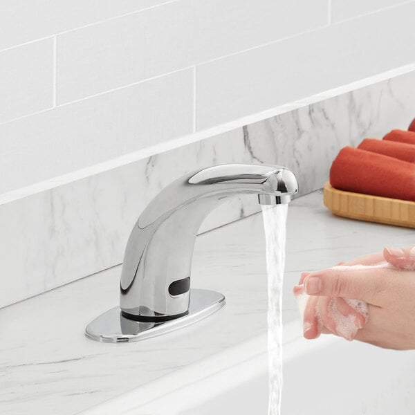 A person washing their hands under a Waterloo deck-mounted hands-free sensor faucet with water running from it.