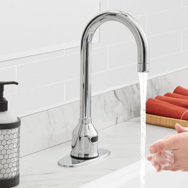 A person washing their hands under a Waterloo hands-free faucet with a gooseneck spout.