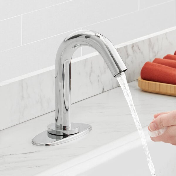 A person's soapy hand washing under a Waterloo hands-free faucet on a counter.