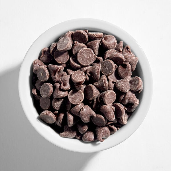 A white bowl filled with semi-sweet chocolate baking chips.