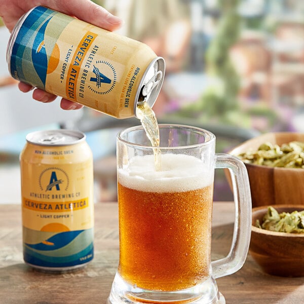 A hand pouring Athletic Brewing Co. Cerveza Athletica into a glass.