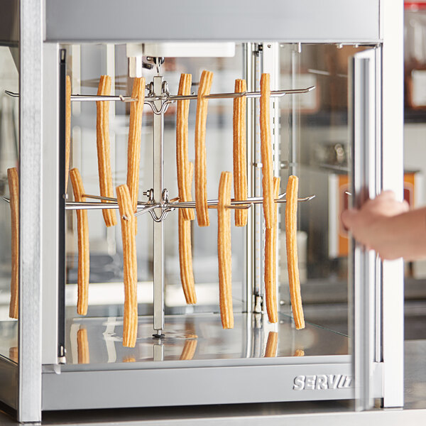 A hand holding a metal bar with food in a machine.