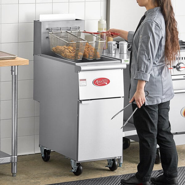 A woman standing in a kitchen with a deep fryer.