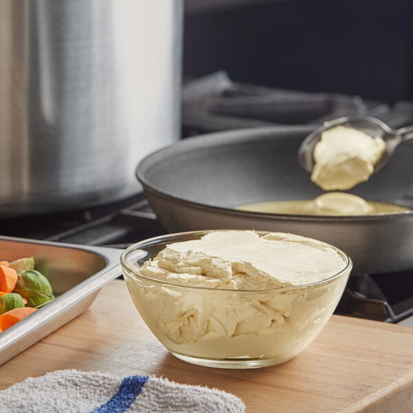 A bowl of Melt Organic salted butter being poured into a pan of vegetables.