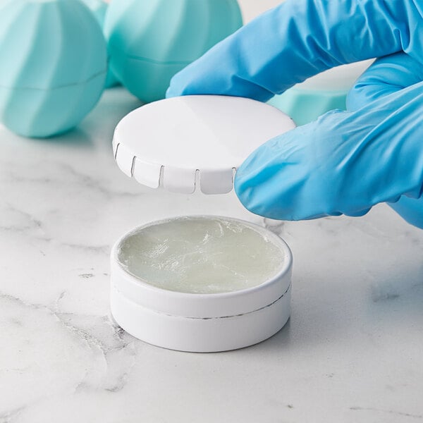 Gloved hands holding a white tin with a push and pop cover containing white pills.