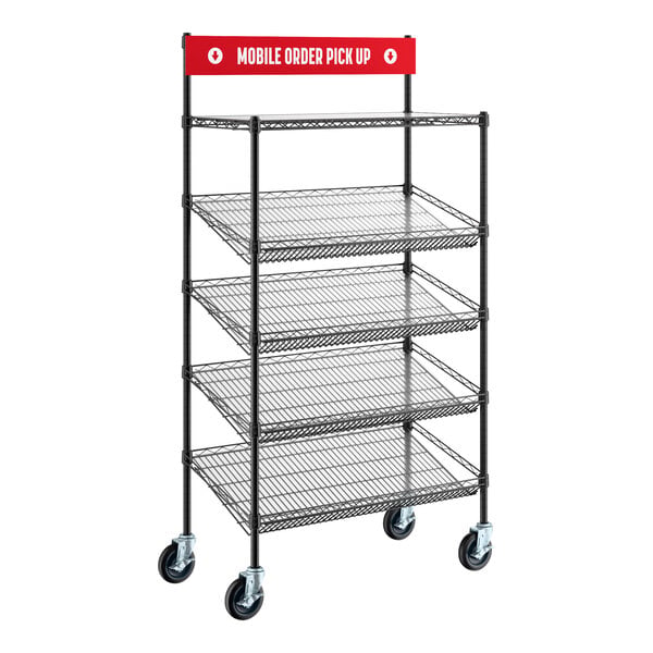 A black metal shelving unit with four slanted wire baskets, one flat top shelf, caster wheels, and a red sign reading 'Mobile Order Pick Up' at the top.