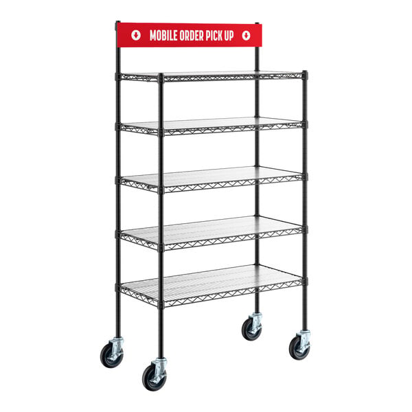 A black metal shelving unit with five wire shelves, four caster wheels, and a red sign on top that reads 'Mobile Order Pick Up.'