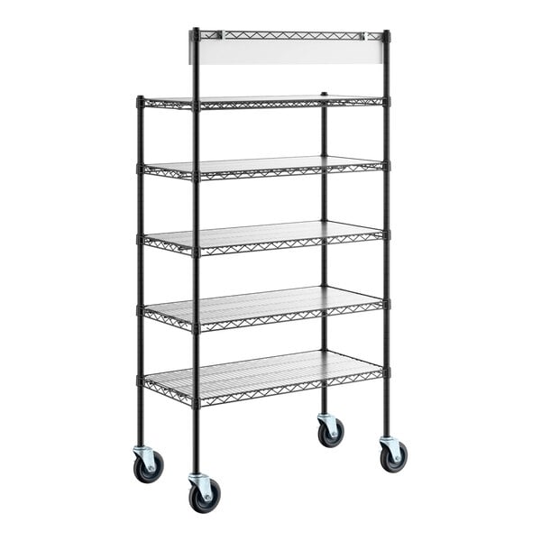 A tall, black metal shelving unit with five wire shelves, a top sign holder, and four caster wheels for mobility.