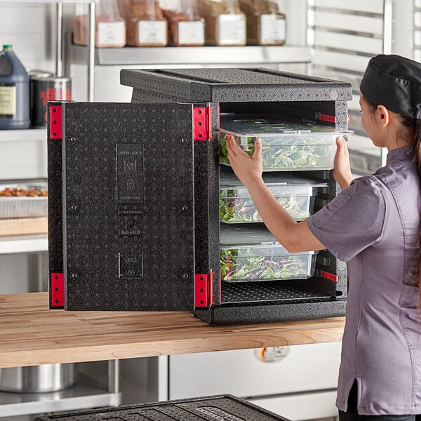 A woman using a CaterGator Dash front loading food pan carrier to store food.