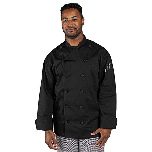 A man wearing a black Uncommon Chef long sleeve chef coat standing in a professional kitchen.