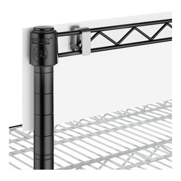 A close-up view of a black metal shelving unit with a wire shelf and a white panel attached to the back using a clamp.