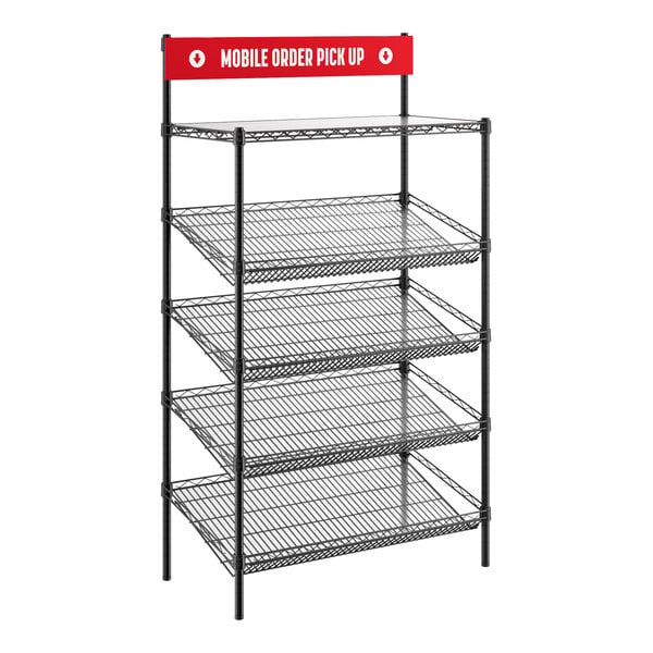 A black metal shelving unit with four slanted wire baskets, one flat top shelf, and a red sign reading 'Mobile Order Pick Up' at the top.