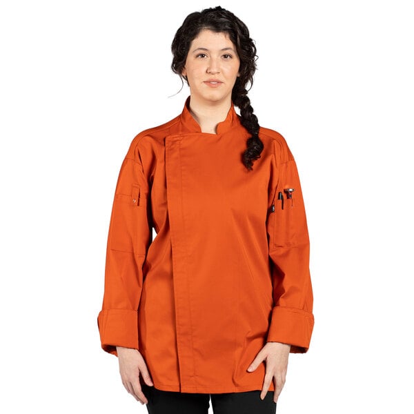 A woman wearing an orange Uncommon Chef long sleeve chef coat with mesh back.