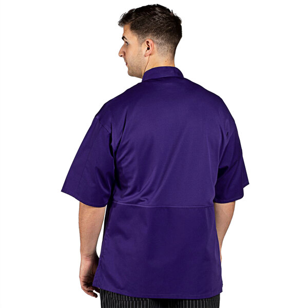 A man wearing a grape Uncommon Chef Venture Pro chef coat with black pants.