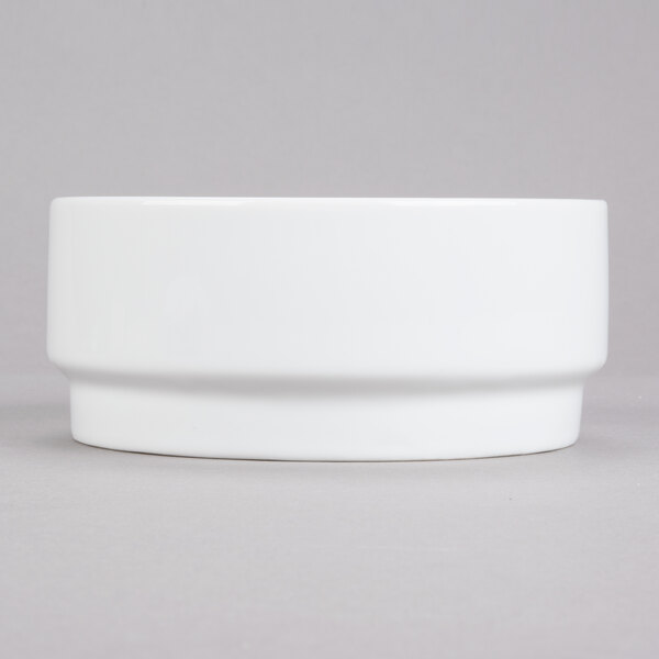A stackable white porcelain bowl with a small rim on a gray surface.