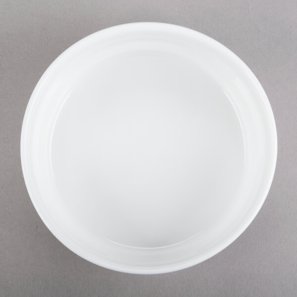 An Arcoroc white porcelain bowl on a gray surface.