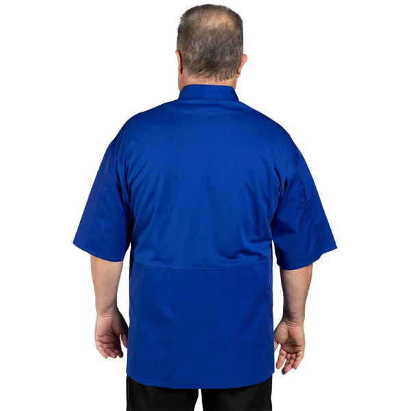 A man wearing a deep royal blue Uncommon Chef Venture Pro Vent chef coat with mesh back.
