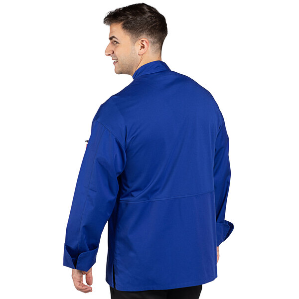 A man wearing an Uncommon Chef deep royal blue long sleeve chef coat with a mesh back.