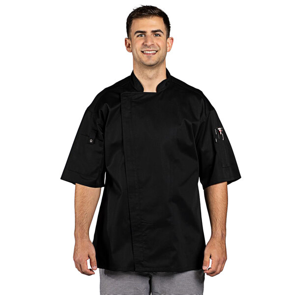 A man wearing a black Uncommon Chef Venture Pro Vent chef coat.