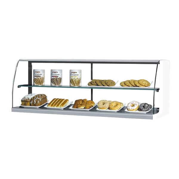 A white 63-inch top dry display case with glass front and shelves, shown holding various baked goods and snacks.