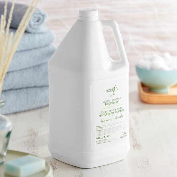 A white bottle of Nourish lemongrass body lotion on a table next to towels.