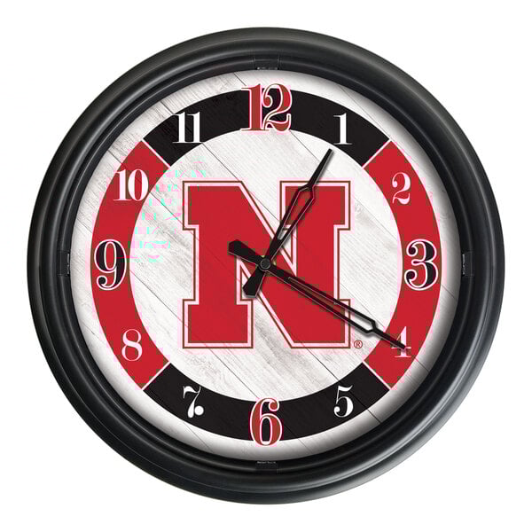 A round wall clock featuring the University of Nebraska logo with a black frame and red, black, and white accents.