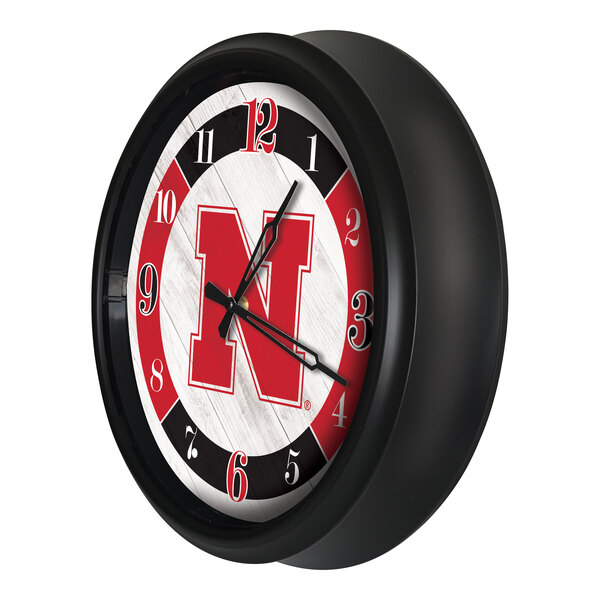 A round wall clock with a black frame featuring the University of Nebraska logo and LED lighting.