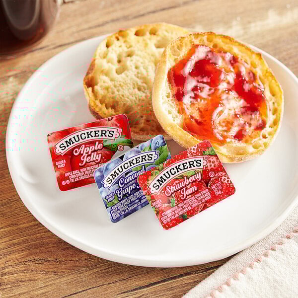 A plate with a bagel and Smucker's jelly on it.