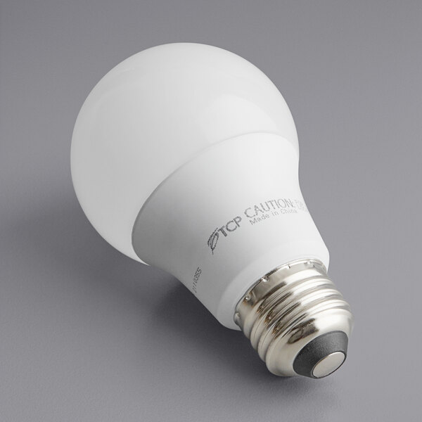 A TCP dimmable LED light bulb in its packaging on a gray surface.