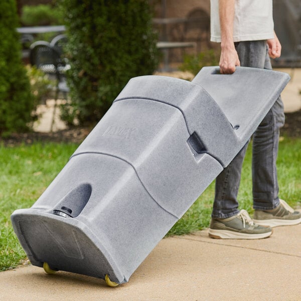 A man pushing a large grey Lavex mobile hand wash station.