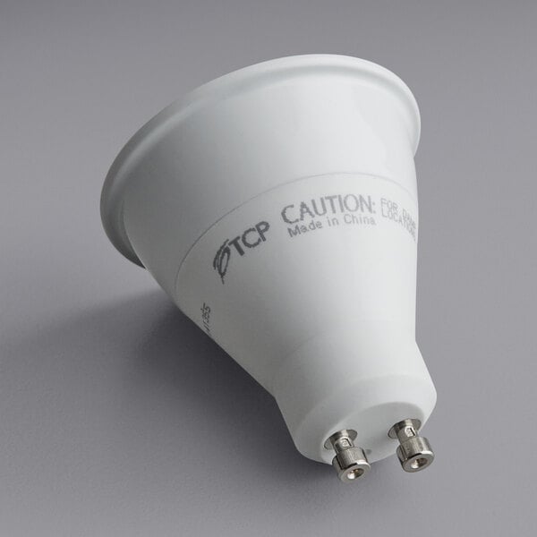 A white TCP LED light bulb with silver tips and black text on the label.