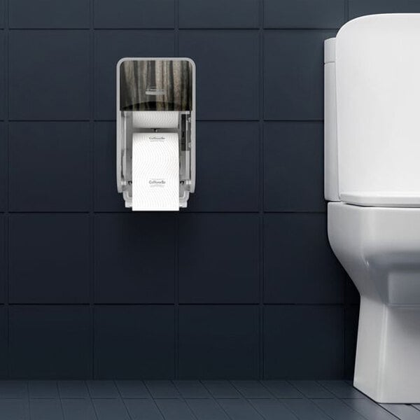 A wall-mounted vertical toilet paper dispenser with a dark woodgrain cover is installed next to a white toilet against a dark tiled wall.