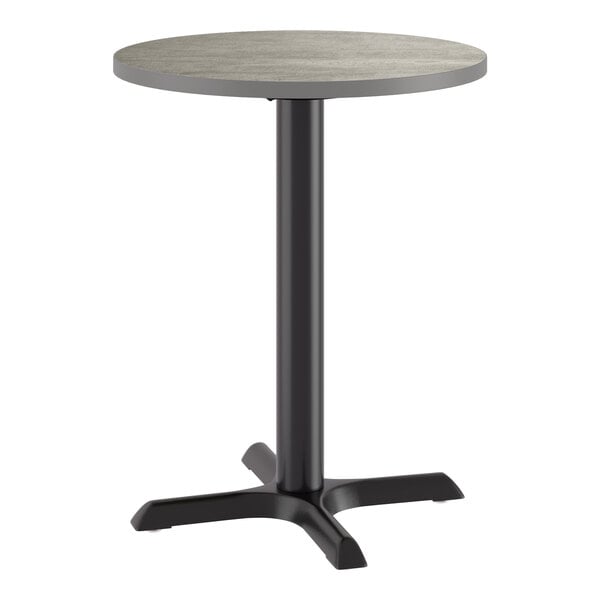 A round standard height table with a reversible gray and white laminated top and a black cast iron base.