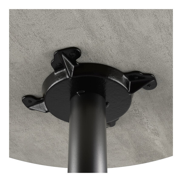 A close-up view of the underside of a table showing a black cast iron base attached to a gray laminated tabletop.