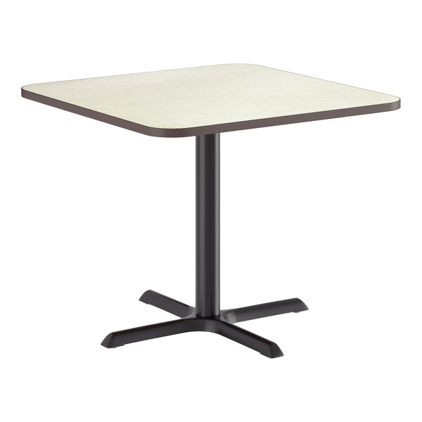 A square standard height table with a reversible white birch or ash laminated top and a black cast iron base.