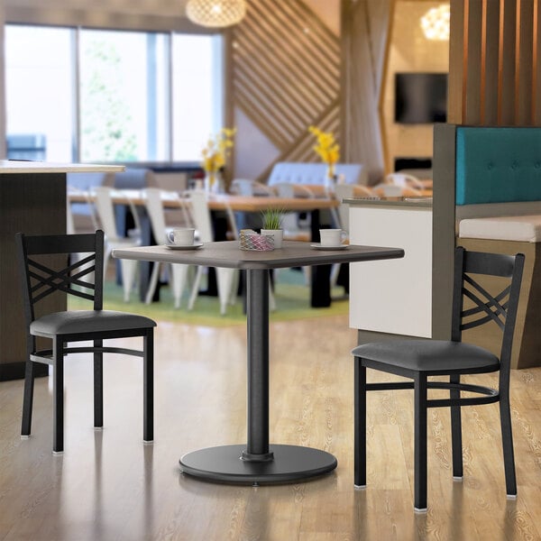 A white Lancaster Table & Seating table top with a white and black reversible pattern on a table with cups on it.