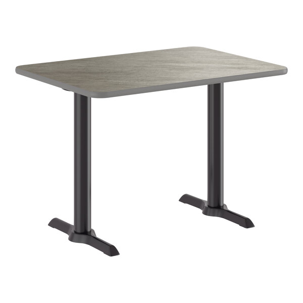 A rectangular table with a reversible gray and white laminated top and a black cast iron base with two pedestal legs.