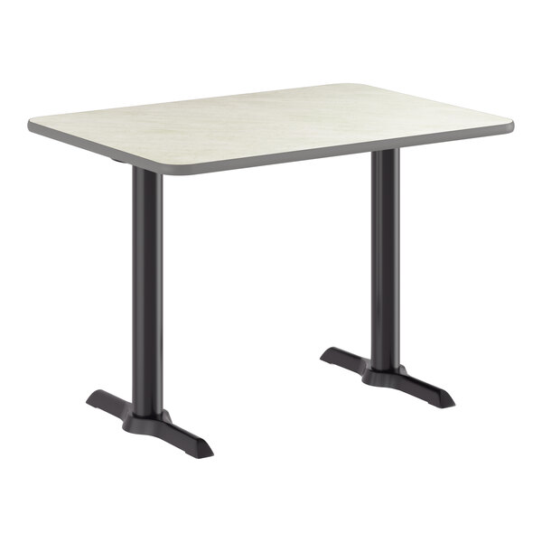 A rectangular table with a reversible gray and white laminated top and a black cast iron base with two legs.