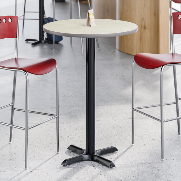 A round bar height table with a reversible gray or white laminated top and a black cast iron base.