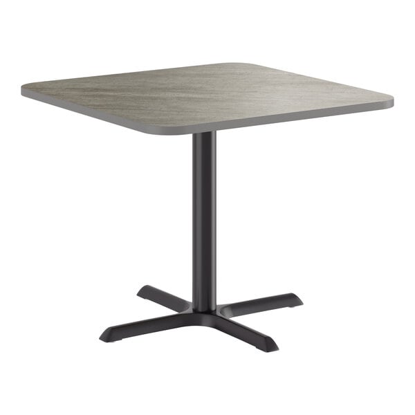 A square standard height table with a reversible gray and white laminated top and a black cast iron base.