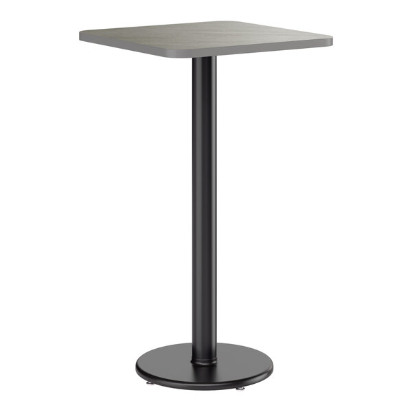 A square bar height table with a reversible gray and white laminated top and a black cast iron base.